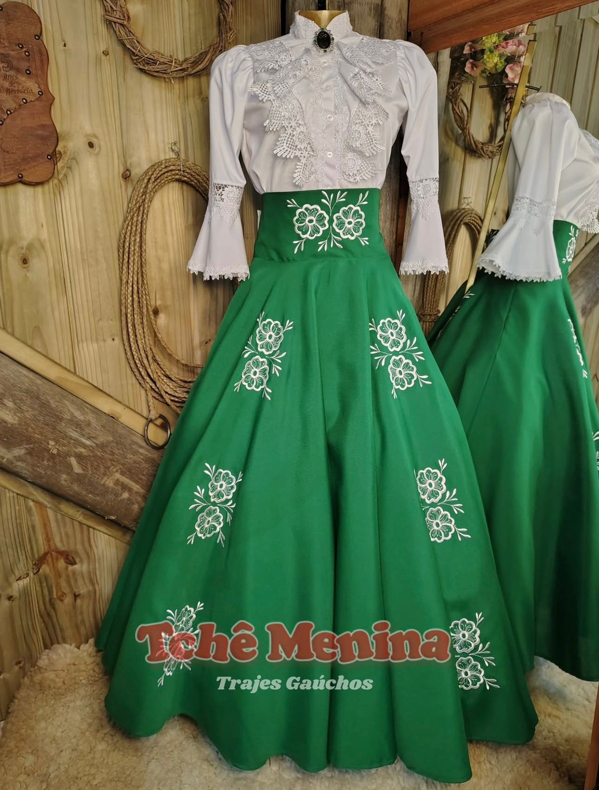 Conjunto de prenda: saia verde bordada e blusa branca de renda no manequim, confecção própria Tchê Menina